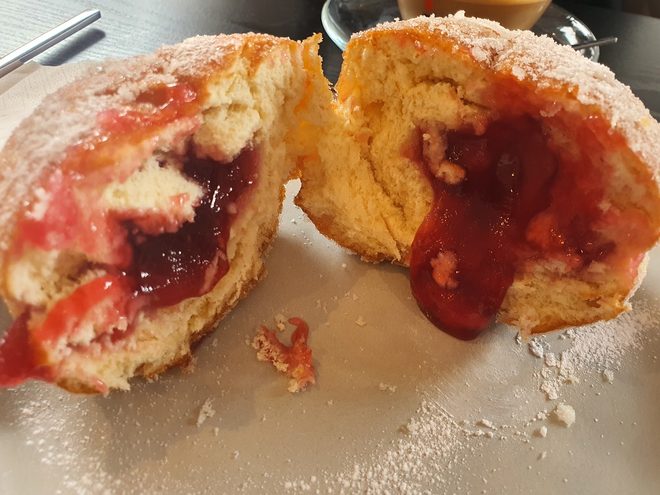A doughnut broken open to show its jam filling
